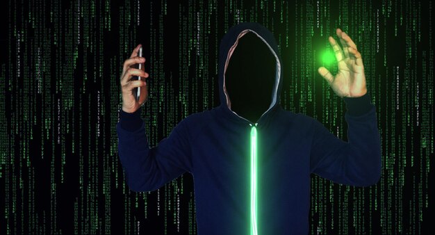 Persona con capucha sosteniendo un teléfono móvil contra el código binario