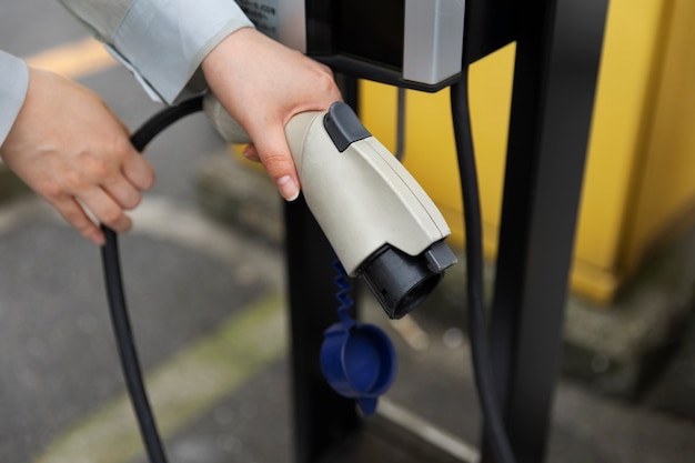 Foto persona con cargador de coche eléctrico