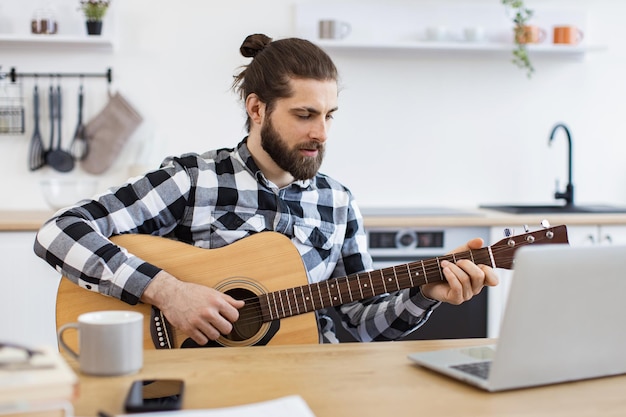 Persona caucásica sosteniendo un instrumento de cuerdas mientras sonríe a la cámara web de la computadora