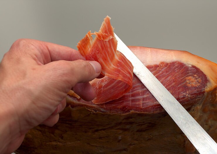 Foto una persona corta con un cuchillo jamonero una deliciosa delicatessen típica de jamón serrano de españa