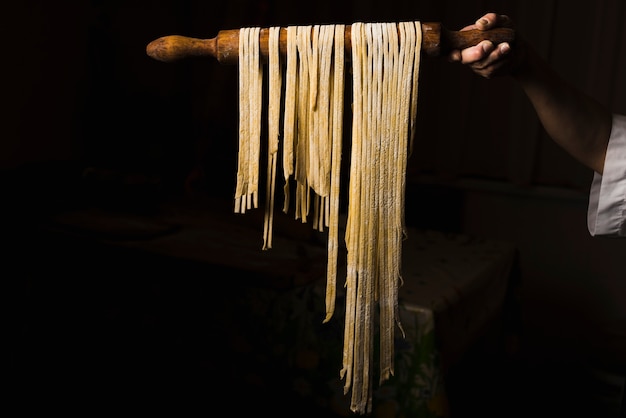 Persona de cultivo con pasta en la cocina oscura