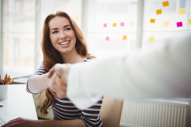 Persona dándose la mano con la empresaria en la oficina creativa