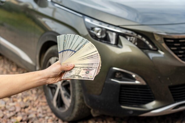 Persona con dinero en la mano se para frente Préstamo de seguro de automóvil y concepto de compra de automóvil