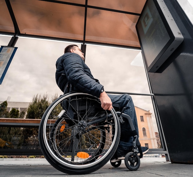 Persona con discapacidad física esperando transporte urbano con rampa accesible