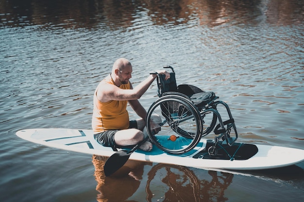 Persona con discapacidad física paseo en sup board con su silla de ruedas