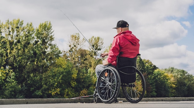Persona con discapacidad física que usa silla de ruedas para pescar desde muelle de pesca
