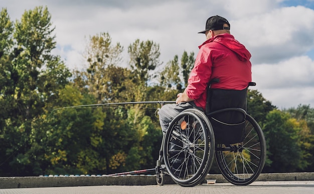 Persona con discapacidad física en silla de ruedas pescando desde muelle de pesca