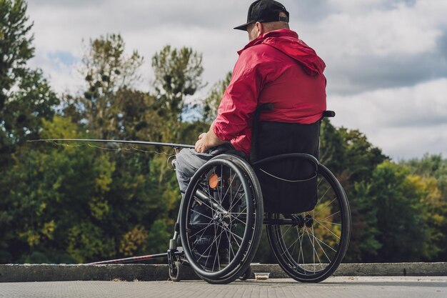 Persona con discapacidad física en silla de ruedas pescando desde muelle de pesca