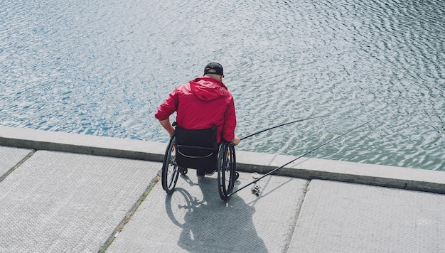 Persona con discapacidad física en silla de ruedas pescando desde muelle de pesca