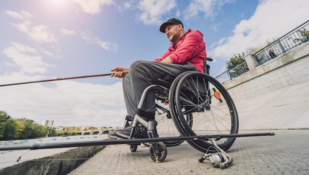 Persona con discapacidad física en silla de ruedas pescando desde muelle de pesca