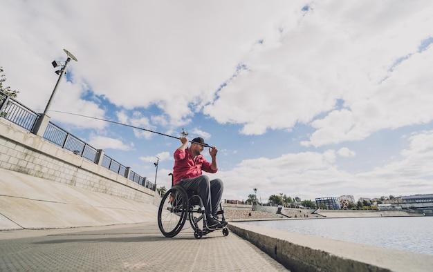 Foto persona con discapacidad física en silla de ruedas pescando desde muelle de pesca