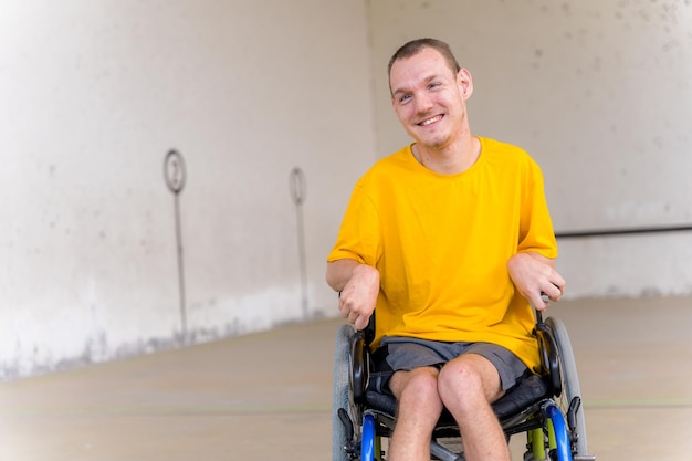 Una persona discapacitada en silla de ruedas en un frontón de pelota vasca sonriendo y divirtiéndose