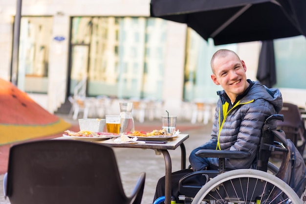 Una persona discapacitada en silla de ruedas en un restaurante sonriendo y divirtiéndose