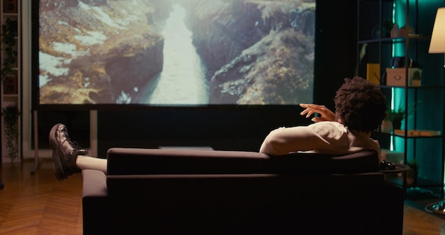 Foto persona disfrutando de las montañas y los ríos tomas de paisajes en el cine en casa relajándose en el sofá