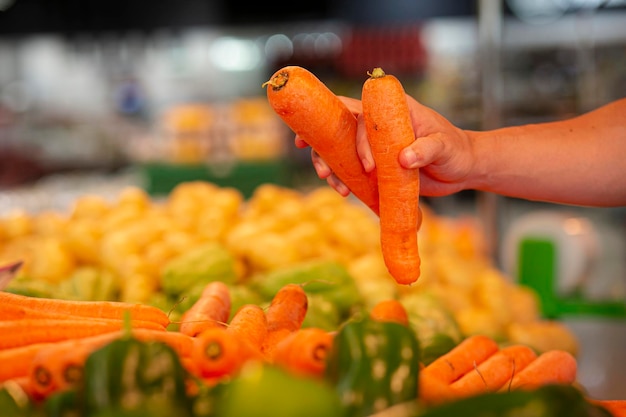 Una persona con dos zanahorias en un mercado.