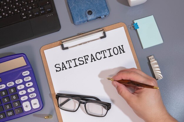una persona escribe la palabra Satisfacción en un papel blanco