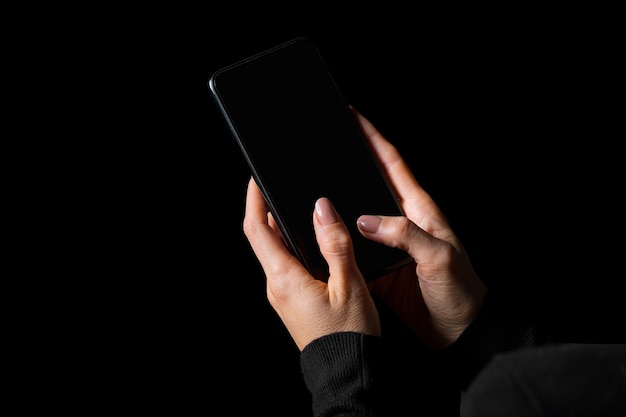 Persona escribiendo algo en el teléfono móvil con una foto de pantalla en blanco aislada en fondo negro