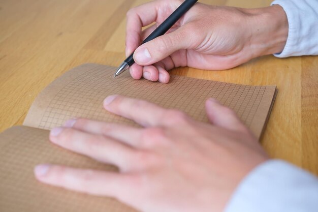 Persona escribiendo con un bolígrafo en un cuaderno de papel antiguo