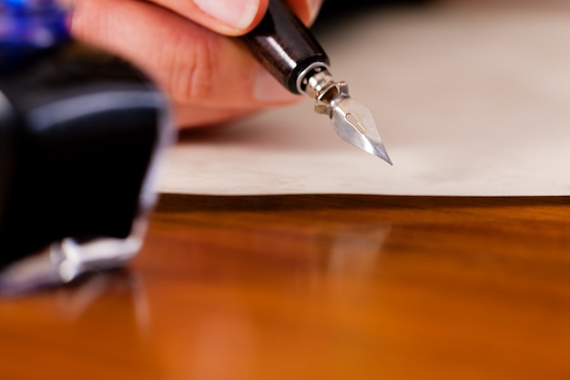 Persona escribiendo una carta con pluma y tinta