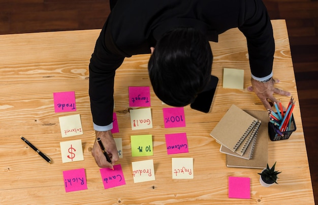 Una persona escribiendo notas post-it en un escritorio.