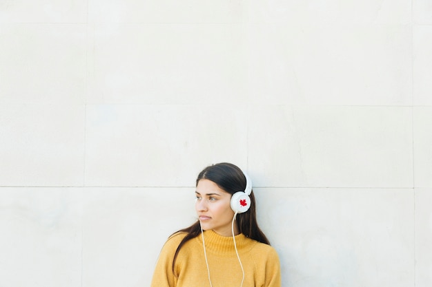 Persona escuchando música en auriculares con hoja de arce de bandera canadiense