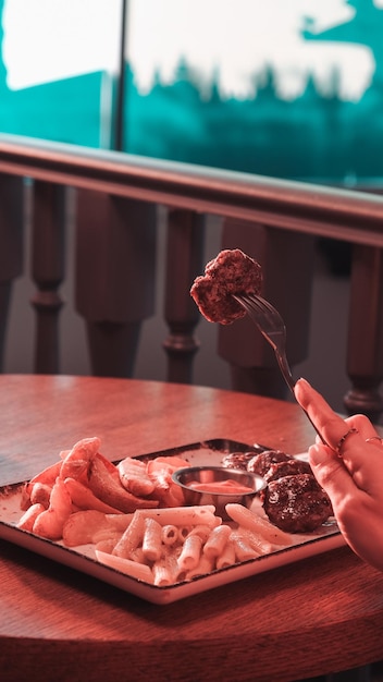 una persona está comiendo una comida con carne en un tenedor