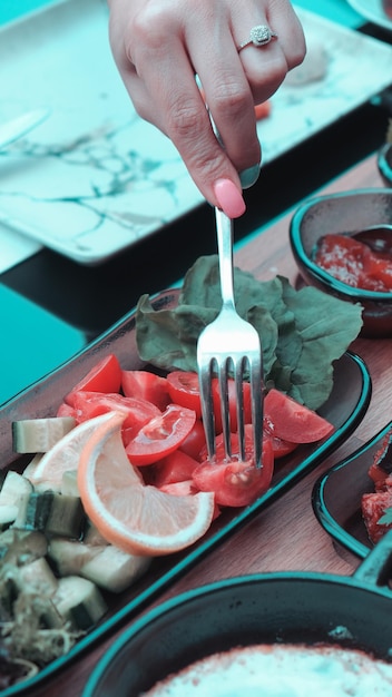 una persona está comiendo un plato de comida con un tenedor y un cuchillo