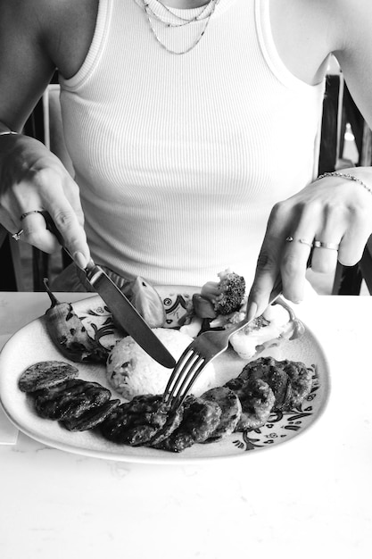 Una persona está cortando comida con un tenedor y un cuchillo.