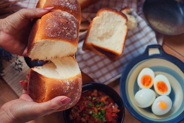 Una persona está cortando pan con un plato de huevos sobre la mesa.