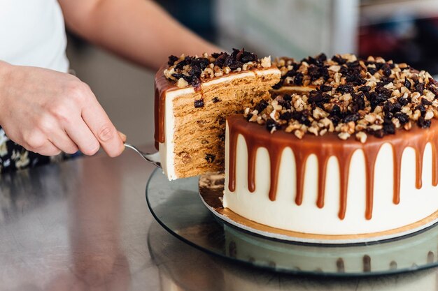 una persona está cortando un pastel con jarabe de chocolate en él