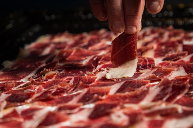 Una persona está cortando un trozo de tocino en una mesa.