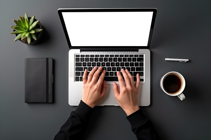 una persona está escribiendo en una computadora portátil con una taza de café y una copa de café