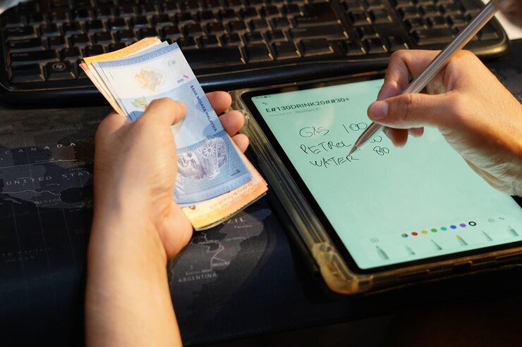 Foto una persona está escribiendo una nota en una tableta con un bolígrafo a su lado mientras sostiene dinero en efectivo