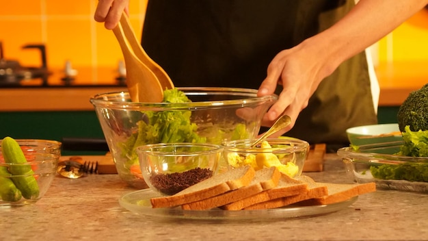 Una persona está poniendo una ensalada en un tazón.