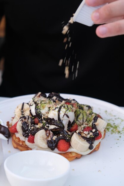 una persona está sosteniendo una cuchara con un plátano y una ensalada de frutas