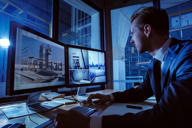 una persona está usando una computadora y explicando la construcción del edificio a otros en el fondo