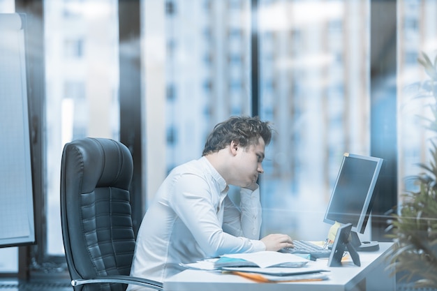 Una persona exhausta en el lugar de trabajo después de una dura jornada de trabajo, cansada de la rutina.