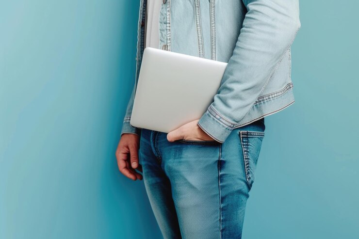 Persona exitosa posando con un netbook en el bolsillo sobre un fondo azul