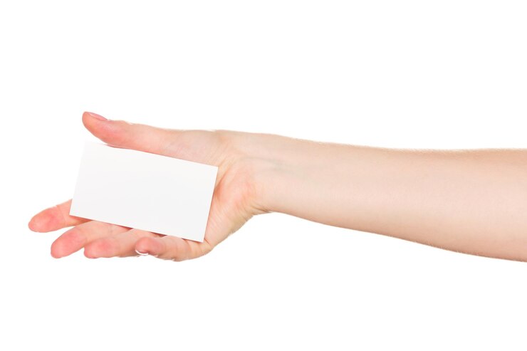 Foto persona extiende la mano sosteniendo una tarjeta en blanco contra un fondo blanco en un entorno minimalista