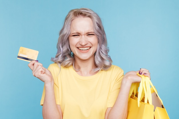 Persona feliz con bolsas de la compra y tarjeta de crédito en el estudio.