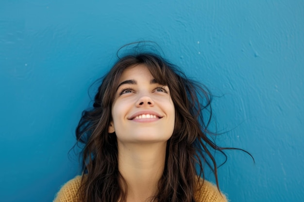 Persona feliz mirando hacia arriba Mujer joven caucásica sonriendo sobre un fondo azul