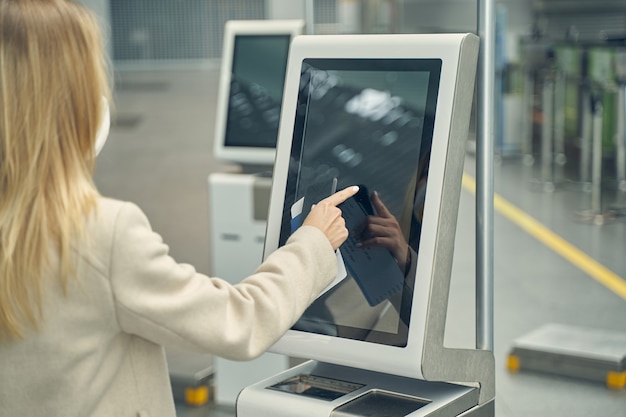 Foto persona femenina atenta tocando la pantalla mientras obtiene su tarjeta de embarque antes del vuelo