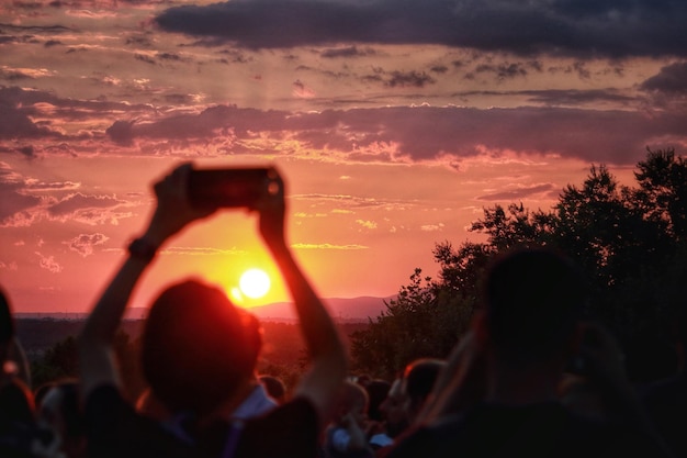 Foto persona fotografiando el cielo durante la puesta de sol