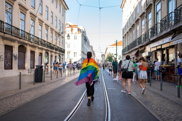 Foto persona gay con bandera arco iris caminando por las calles de lisboa