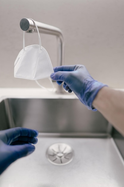 Foto persona con guantes limpiando la mascarilla covid19