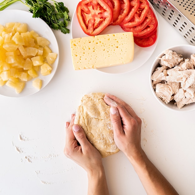 Persona haciendo masa de pizza con ingredientes