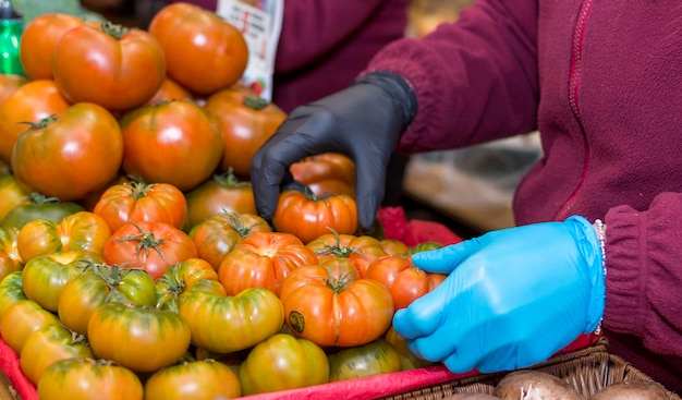 Una persona haciendo un montón de tomates en un mercado.