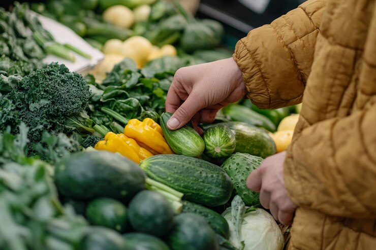 Una persona inspecciona pepinos vibrantes entre verduras de colores en un puesto de mercado