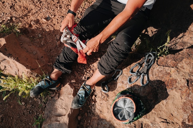 Persona irreconocible poniéndose las cuerdas para escalar. Desde arriba