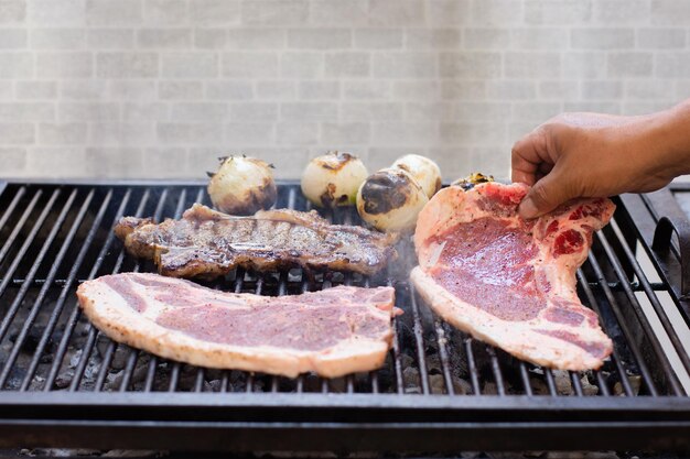 Una persona irreconocible que cocina la barbacoa con algunas cebollas verdes